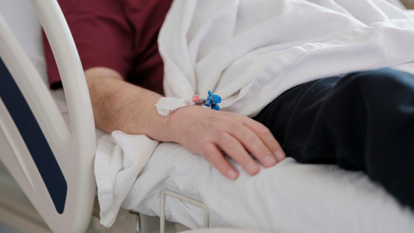 a man laying in a hospital bed with a cast on his arm