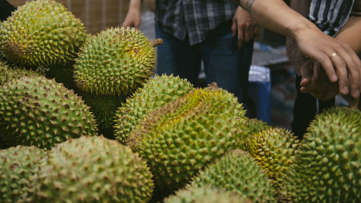 A group of people standing around a pile of fruit