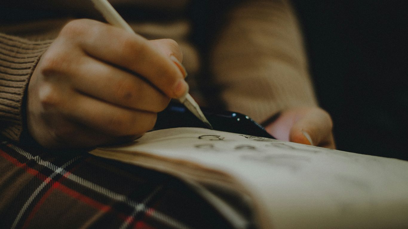 person holding pen and book