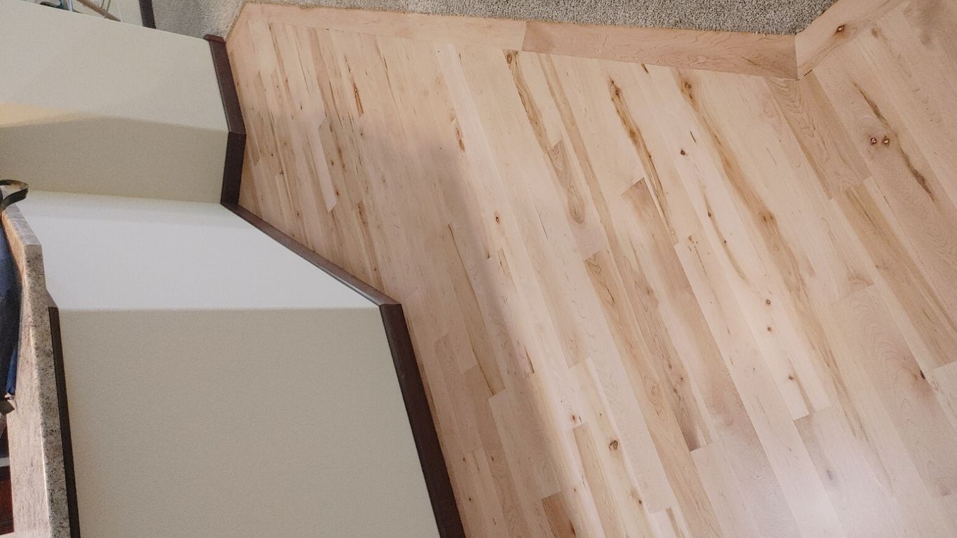 Wooden floor transitioning between two areas in a room.