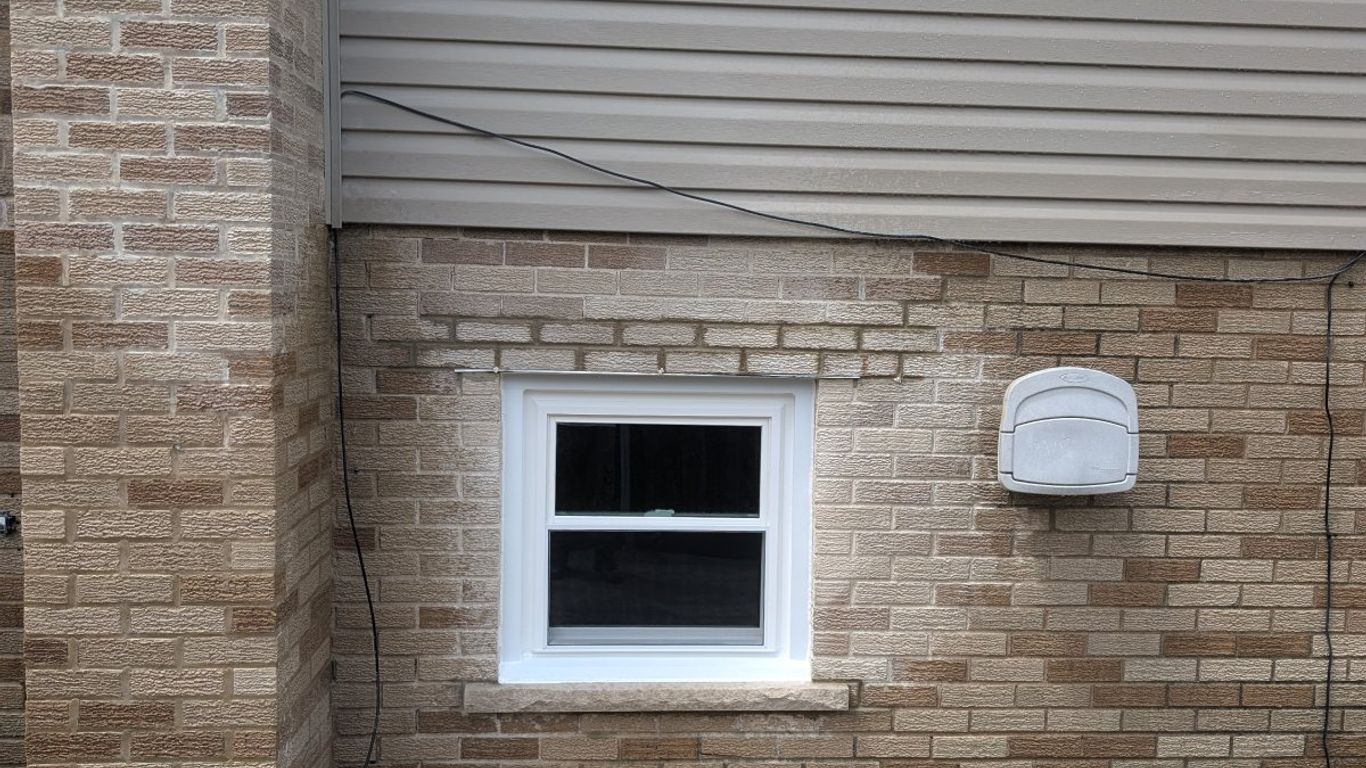 Exterior wall of a building with brick and vinyl siding.