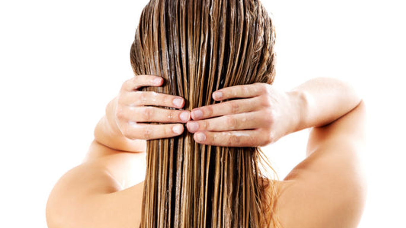 A person applying a treatment to their long, wet hair.