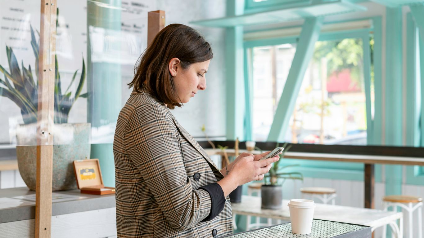 woman in black and white checkered long sleeve shirt using smartphone
