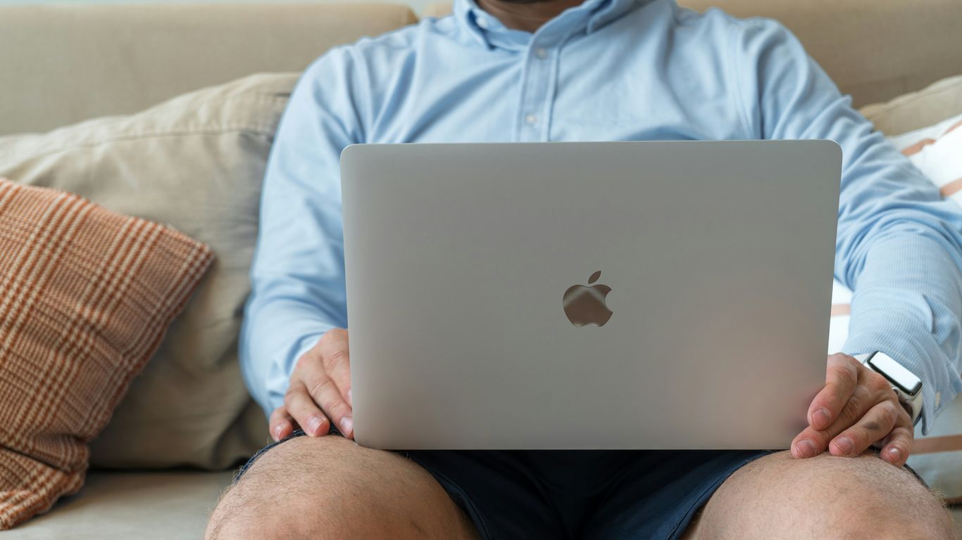a man sitting on a couch holding a laptop