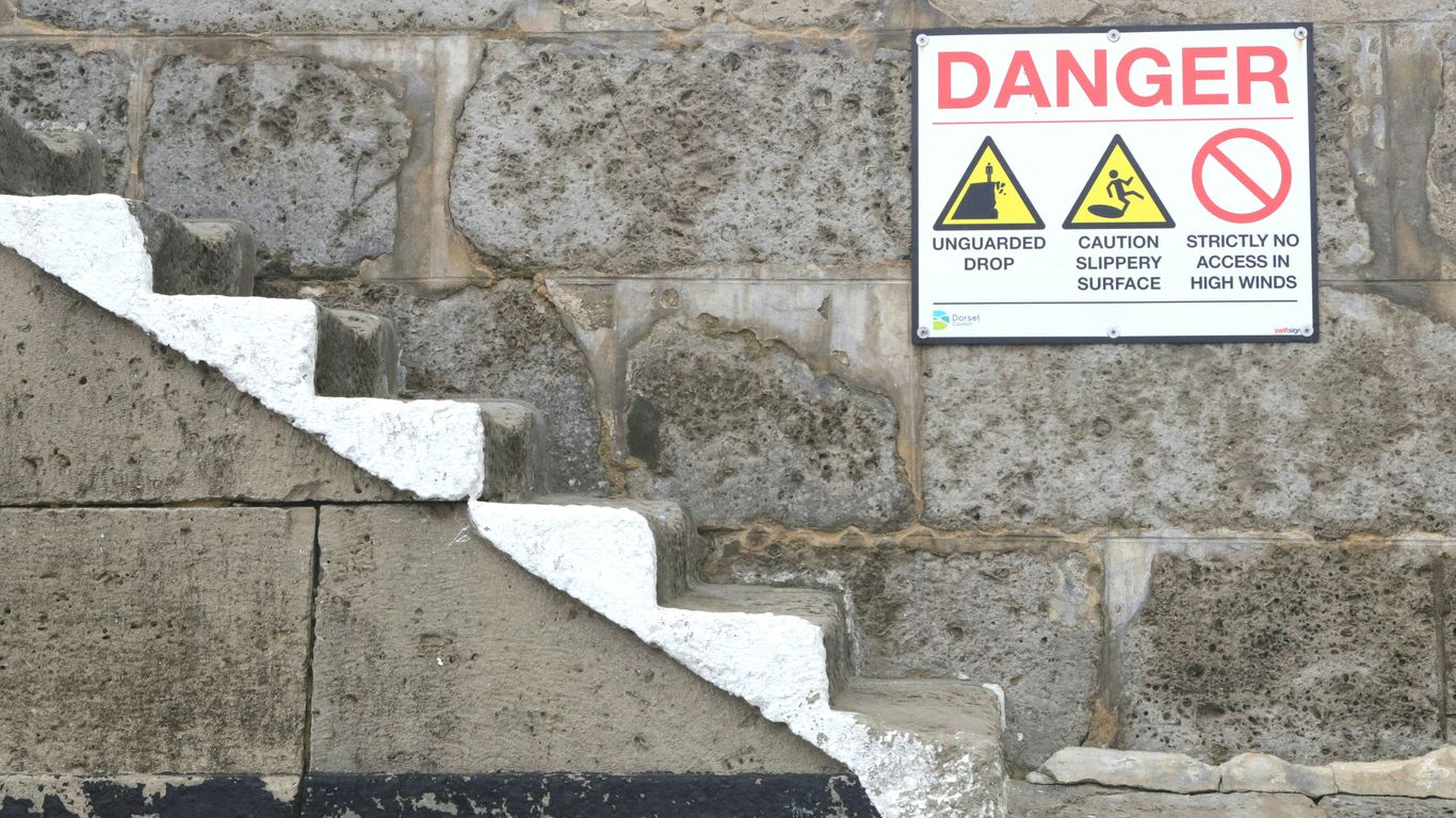 a sign on a stone wall warning of danger