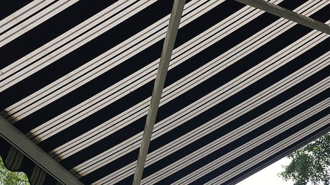 A striped awning with metal supports against a bright sky.
