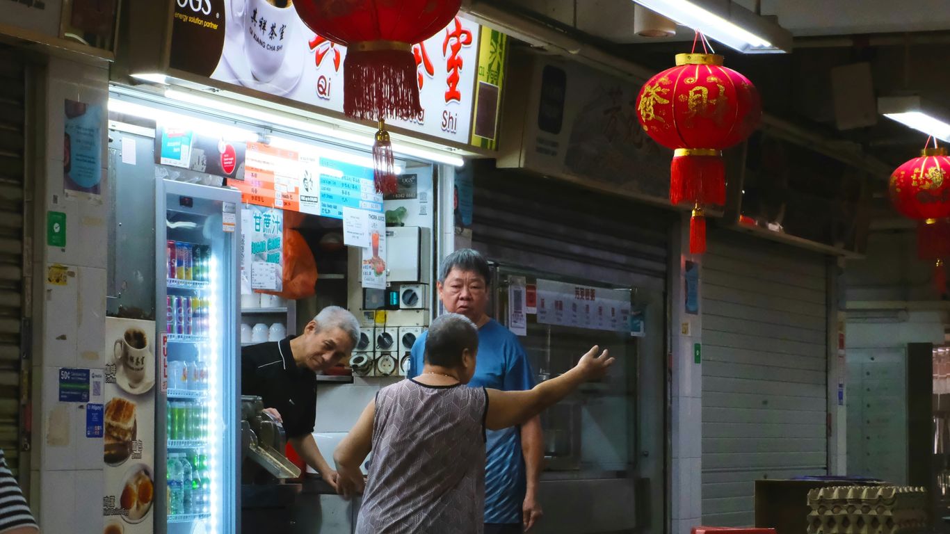 People at a brightly lit street food stall with lanterns