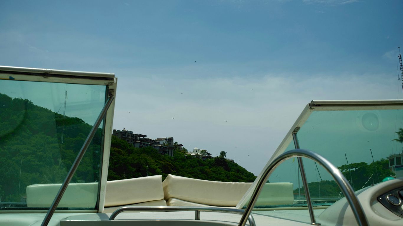 View from a boat looking towards a green hillside.