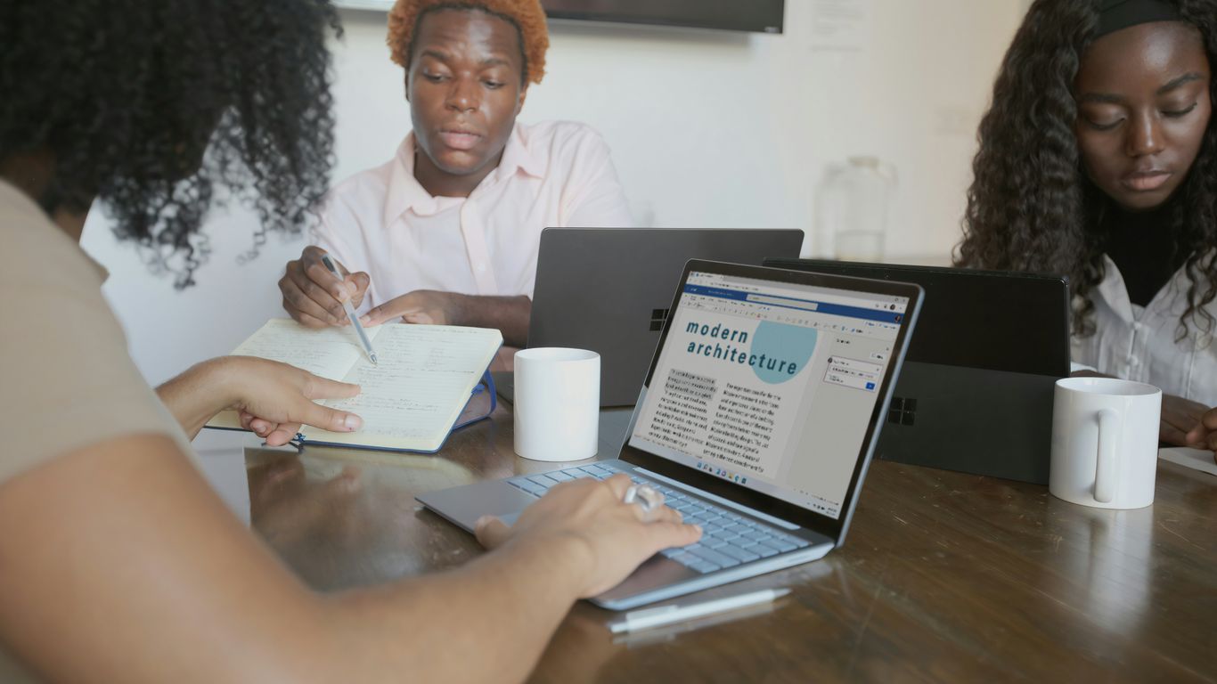 Three people meeting with their Microsoft devices at work 