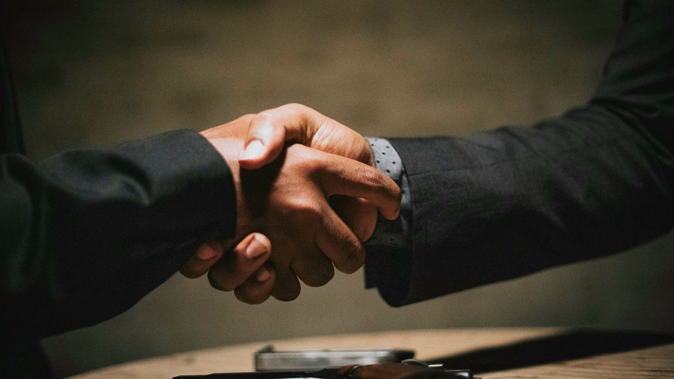 dos personas dándose la mano sobre una mesa de madera