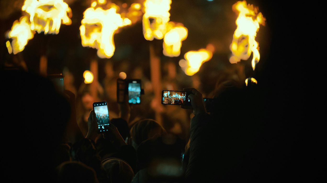 People holding up phones to record a fire performance.
