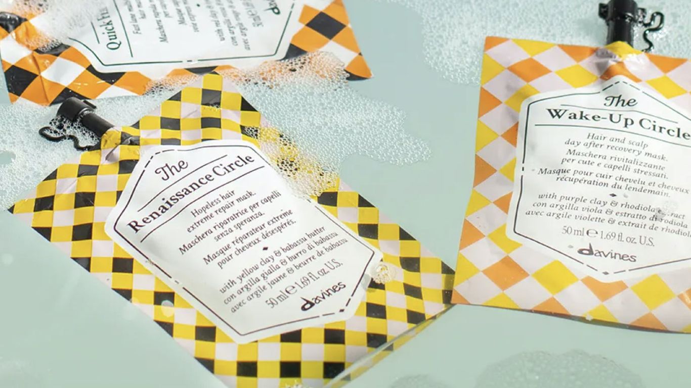 Hair care product sachets floating in water with patterned background.