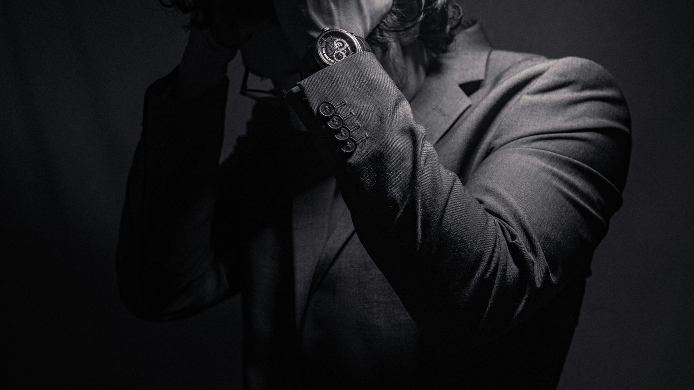 a man in a suit covers his face with his hands