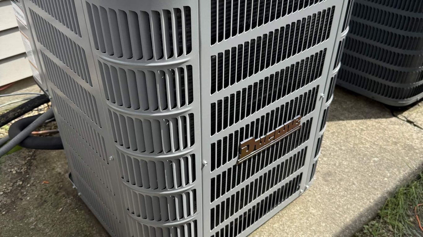 Two outdoor air conditioning units are next to a house.