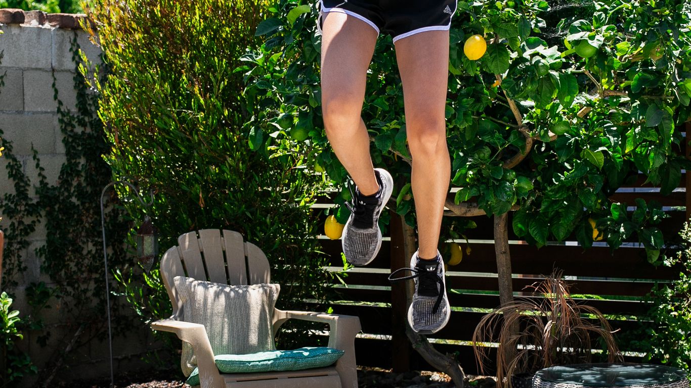 Person jumping on a trampoline in a sunny backyard setting.