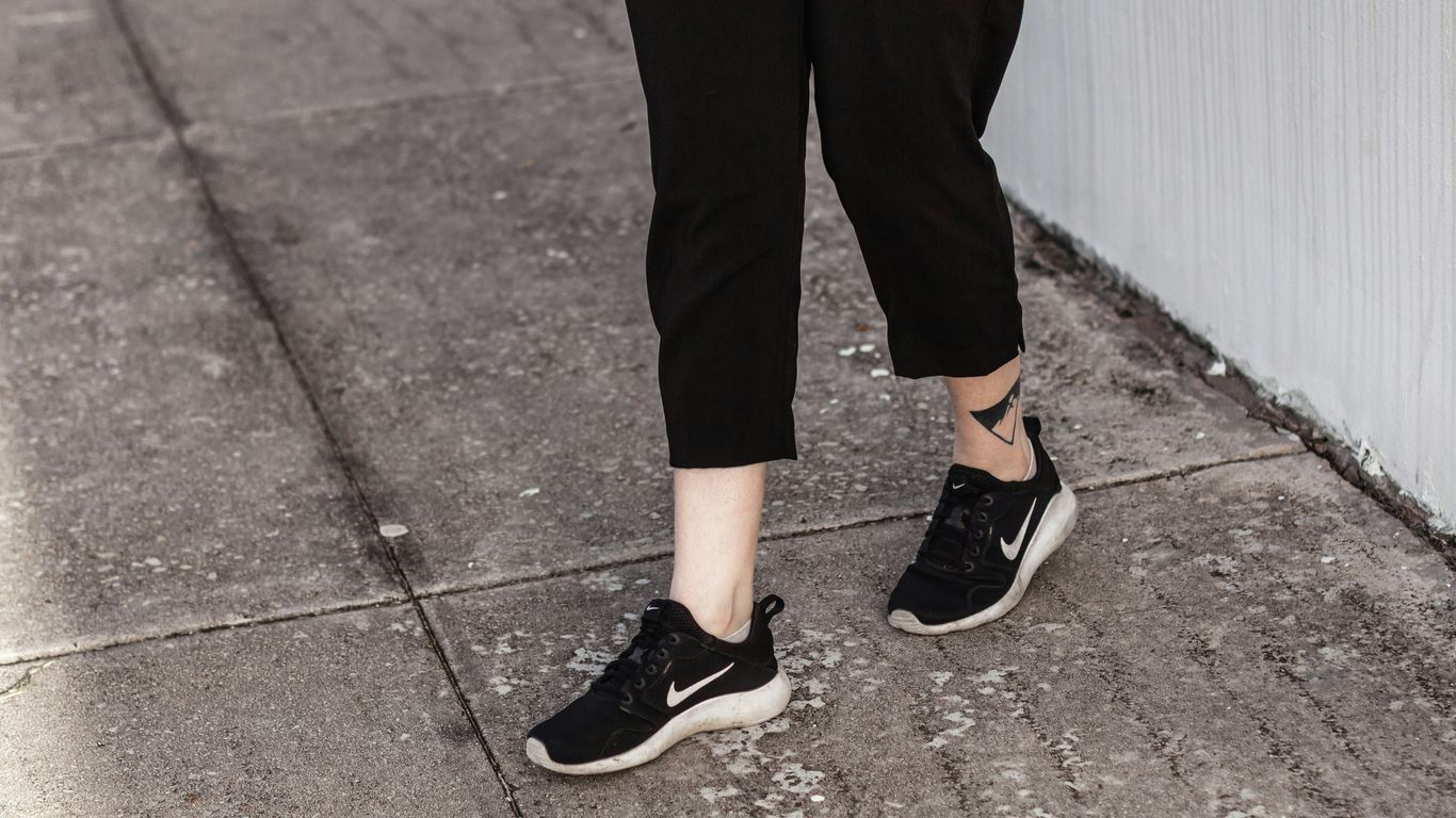 person in black pants and black and white nike sneakers