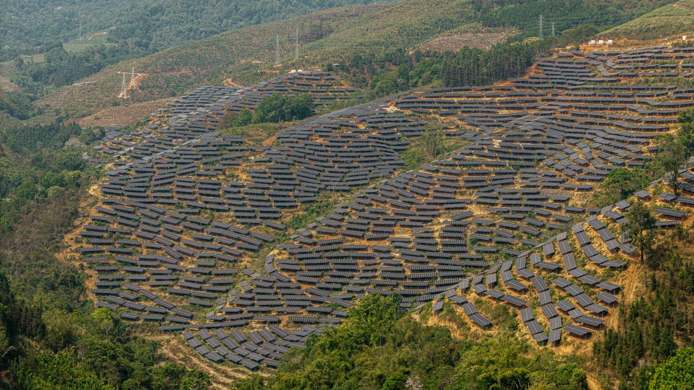 Solar panels cover a hillside in a rural landscape.
