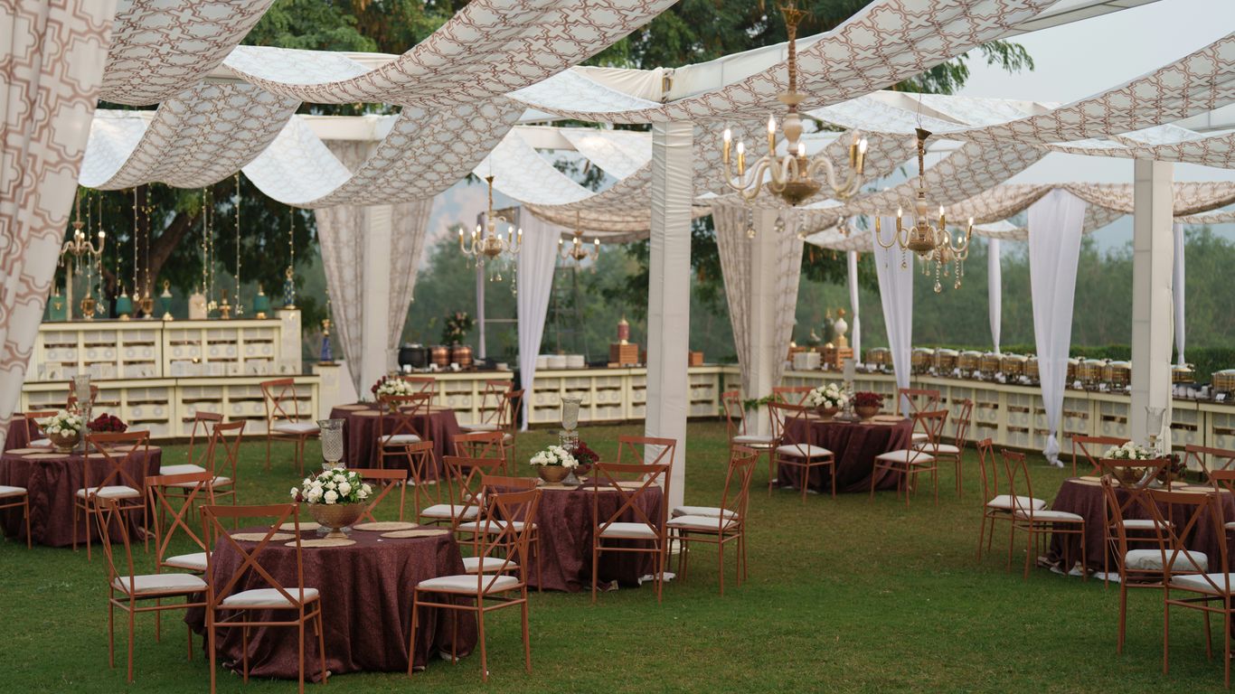 Elegant outdoor wedding reception with draped canopy and tables.