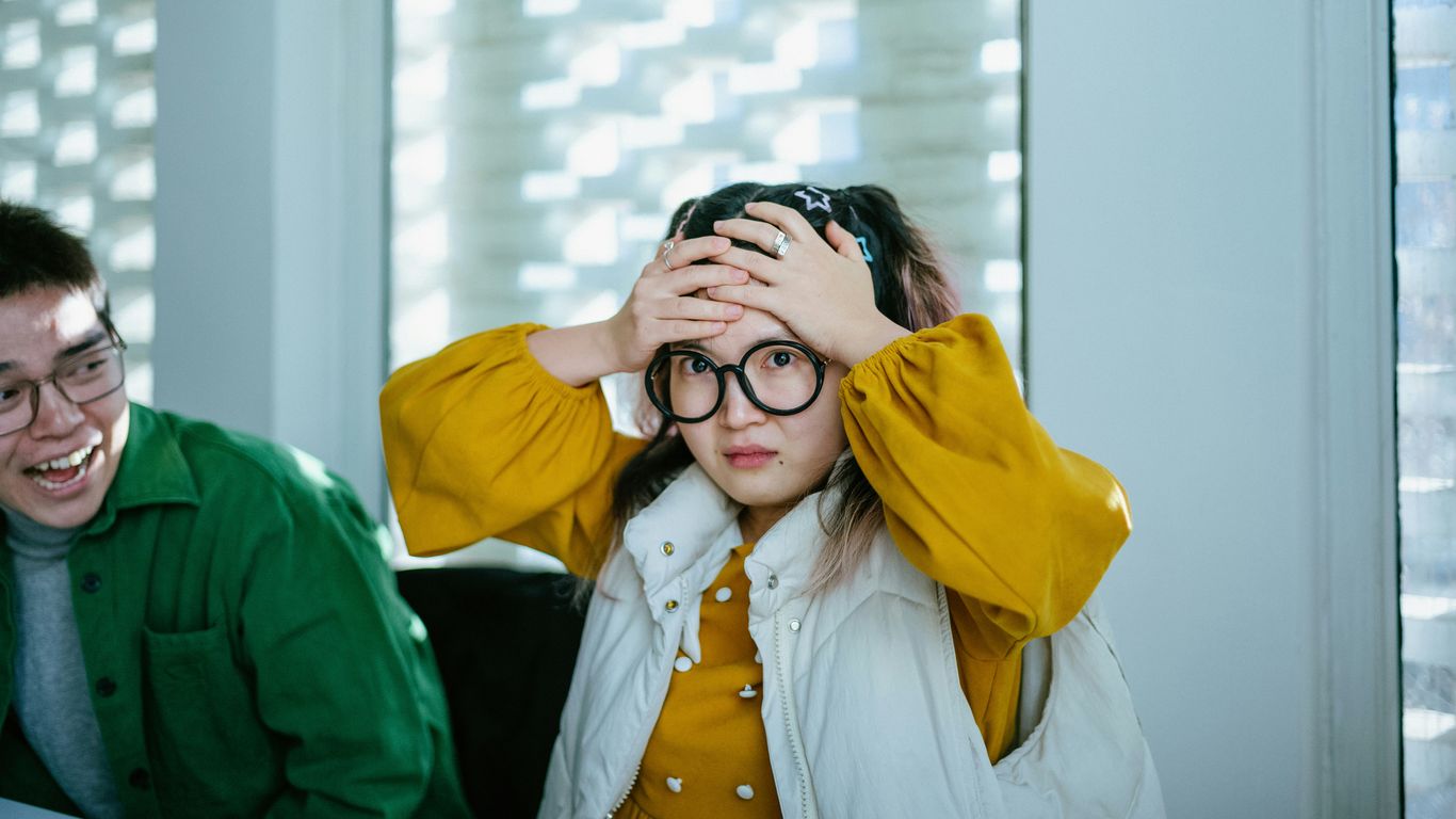 a boy and a girl sitting at a table with a laptop