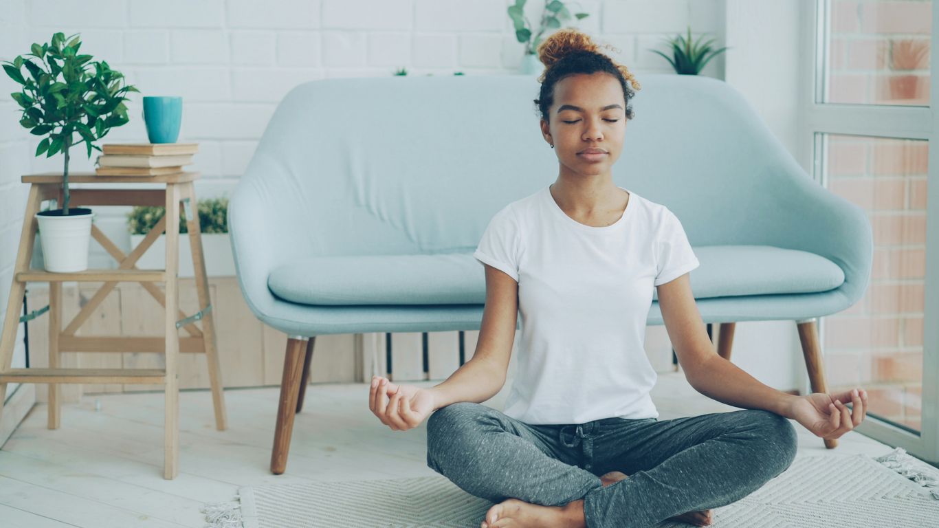 Young woman meditating on the floor at home.