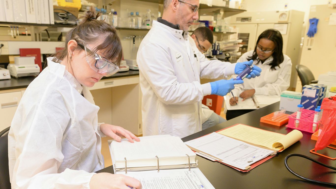 a group of people in lab coats working in a lab