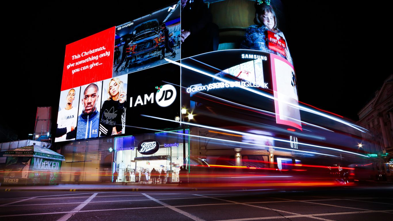 Busy cityscape with illuminated billboards and light trails at night