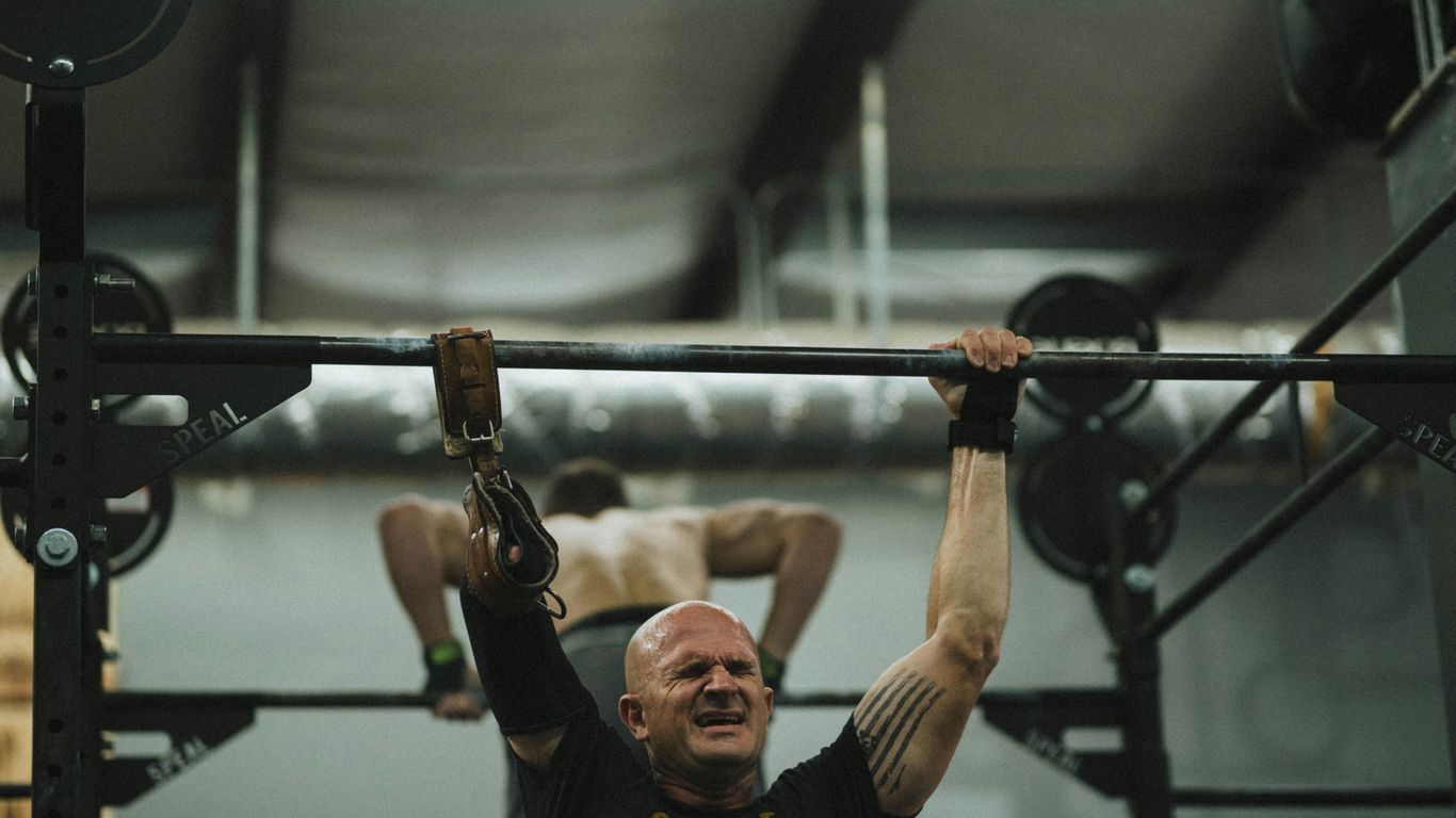 man in black crew neck t-shirt holding black barbell