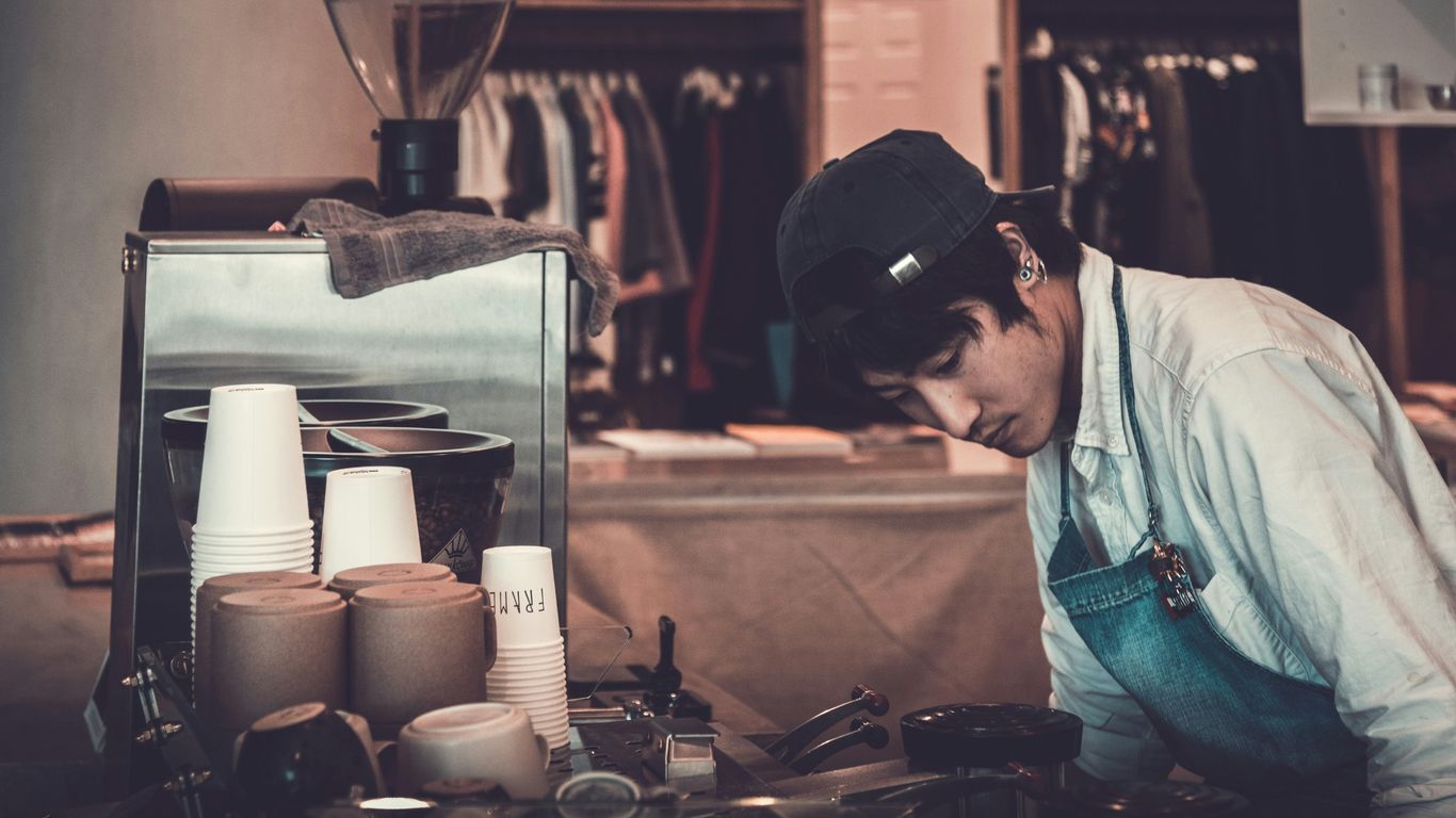 man facing kitchenware and appliances wearing white top and blue apron