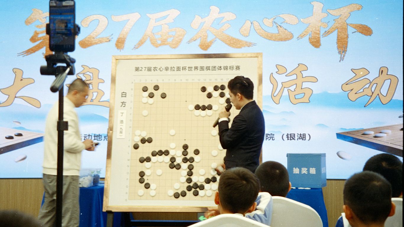 Two men playing go board game with audience watching