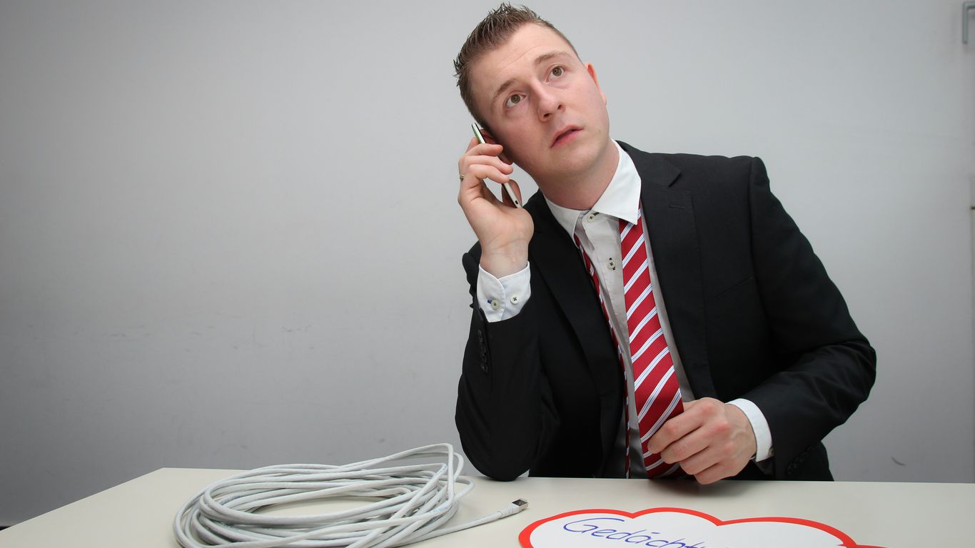 a man sitting at a table talking on a cell phone