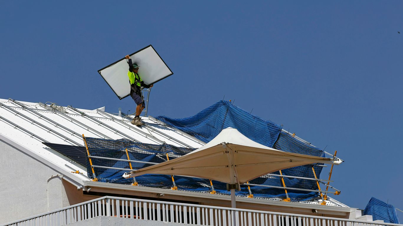 a man on top of a roof fixing a solar panel