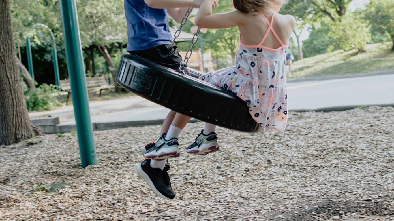 girl in pink and white floral dress riding on swing during daytime
