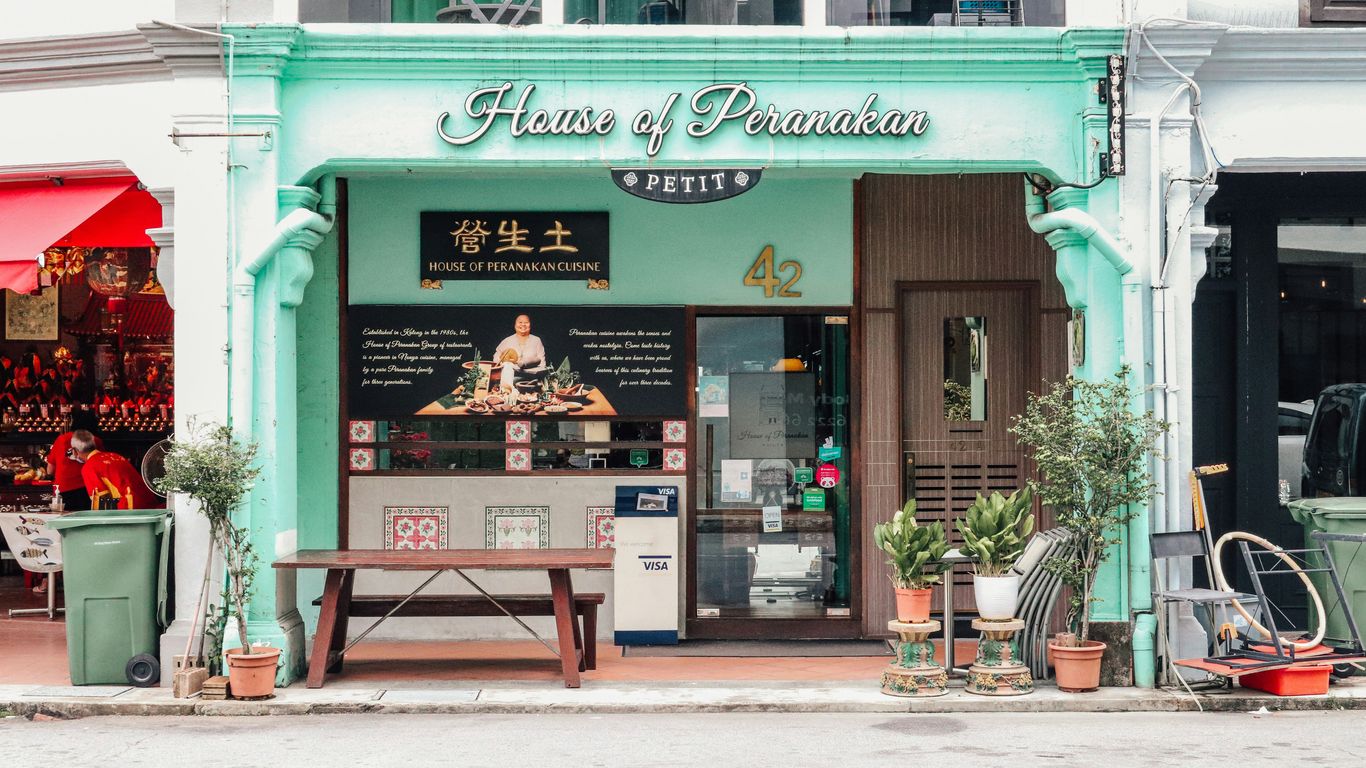 a store front with a green awning and a wooden bench in front of it