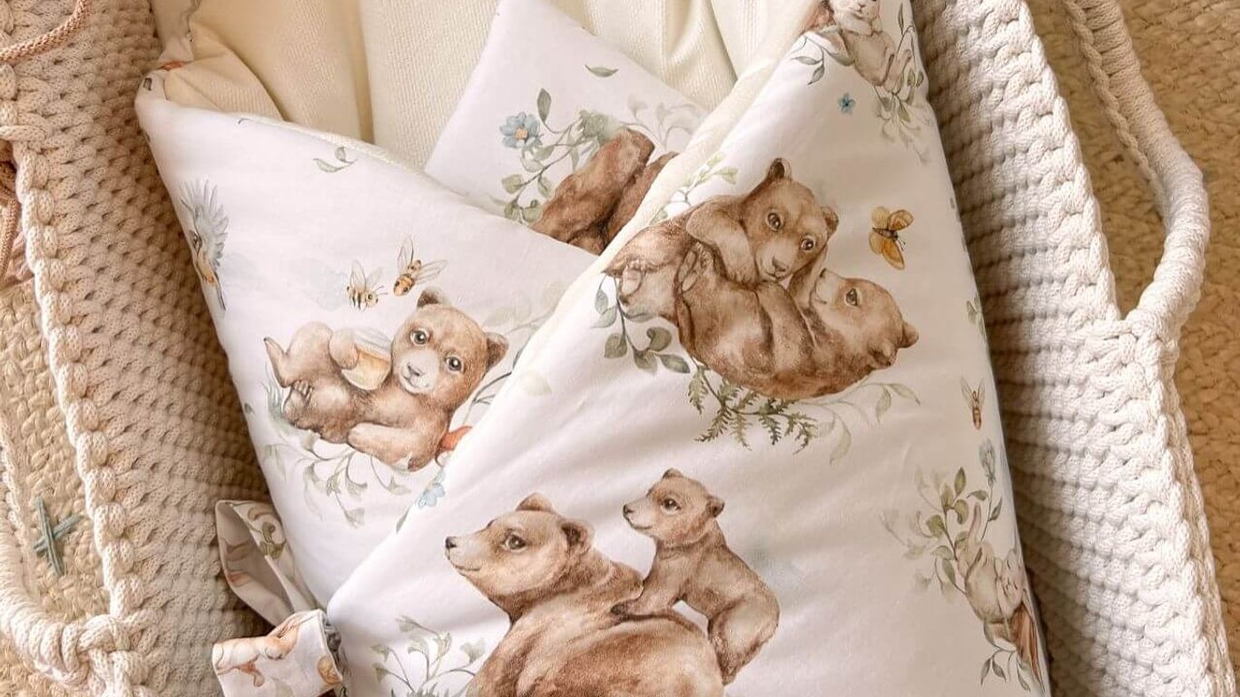 A bassinet with a baby wrapped in a blanket with bear illustrations.