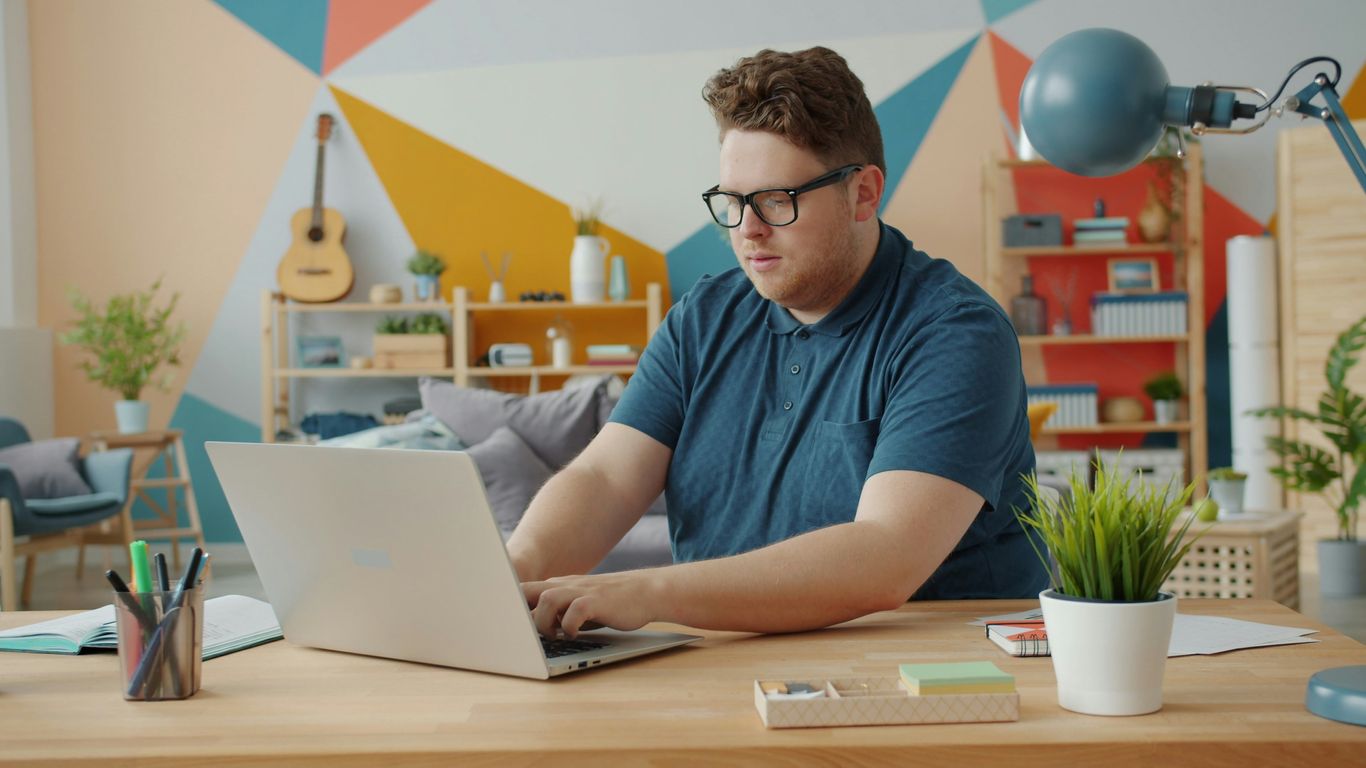Man working on laptop at a colorful desk.