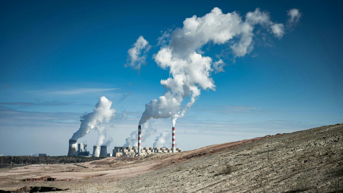 Industrial power plant emitting smoke under a clear blue sky.