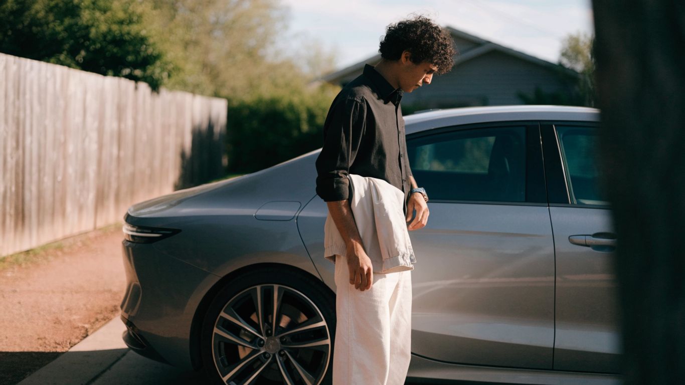 Driver considering upgrades beside a parked car
