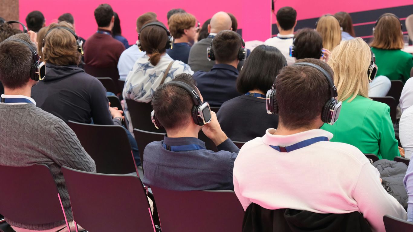 A group of people sitting in front of a pink wall