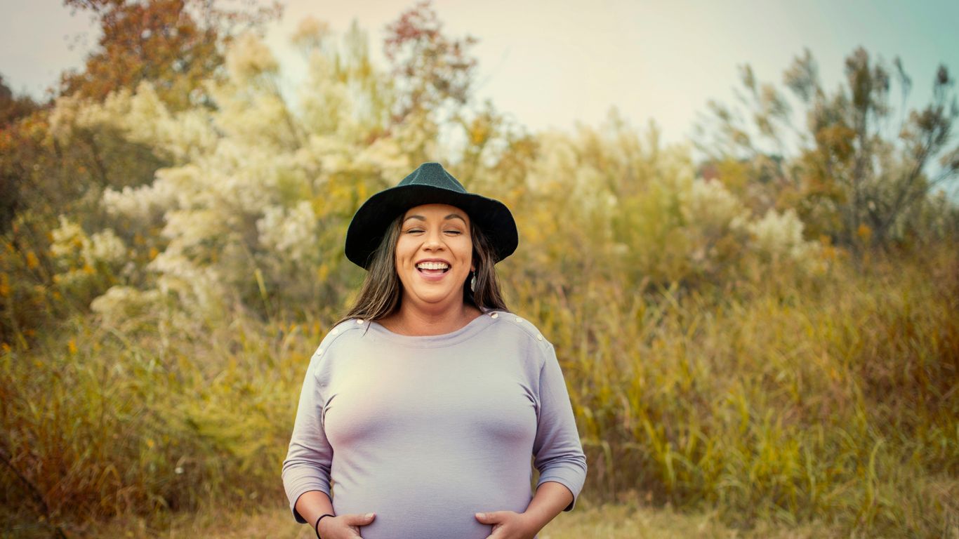 woman in white long sleeve shirt and black hat standing on brown grass field during daytime
