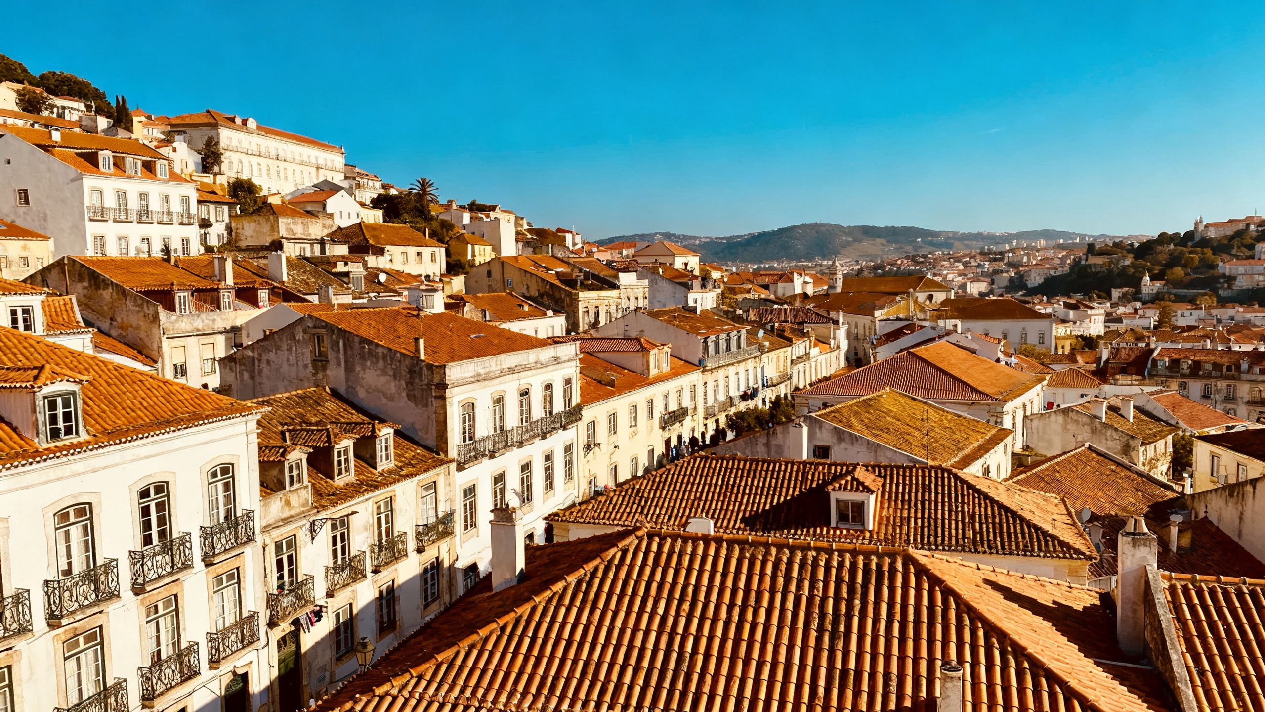 Lisbon cityscape with traditional rooftops under a clear sky.