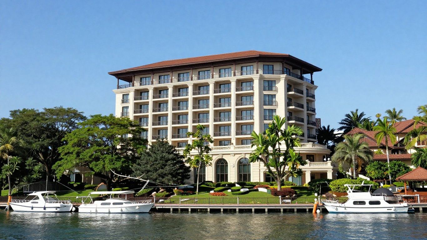 Elegant waterfront hotel with lush greenery and blue sky.