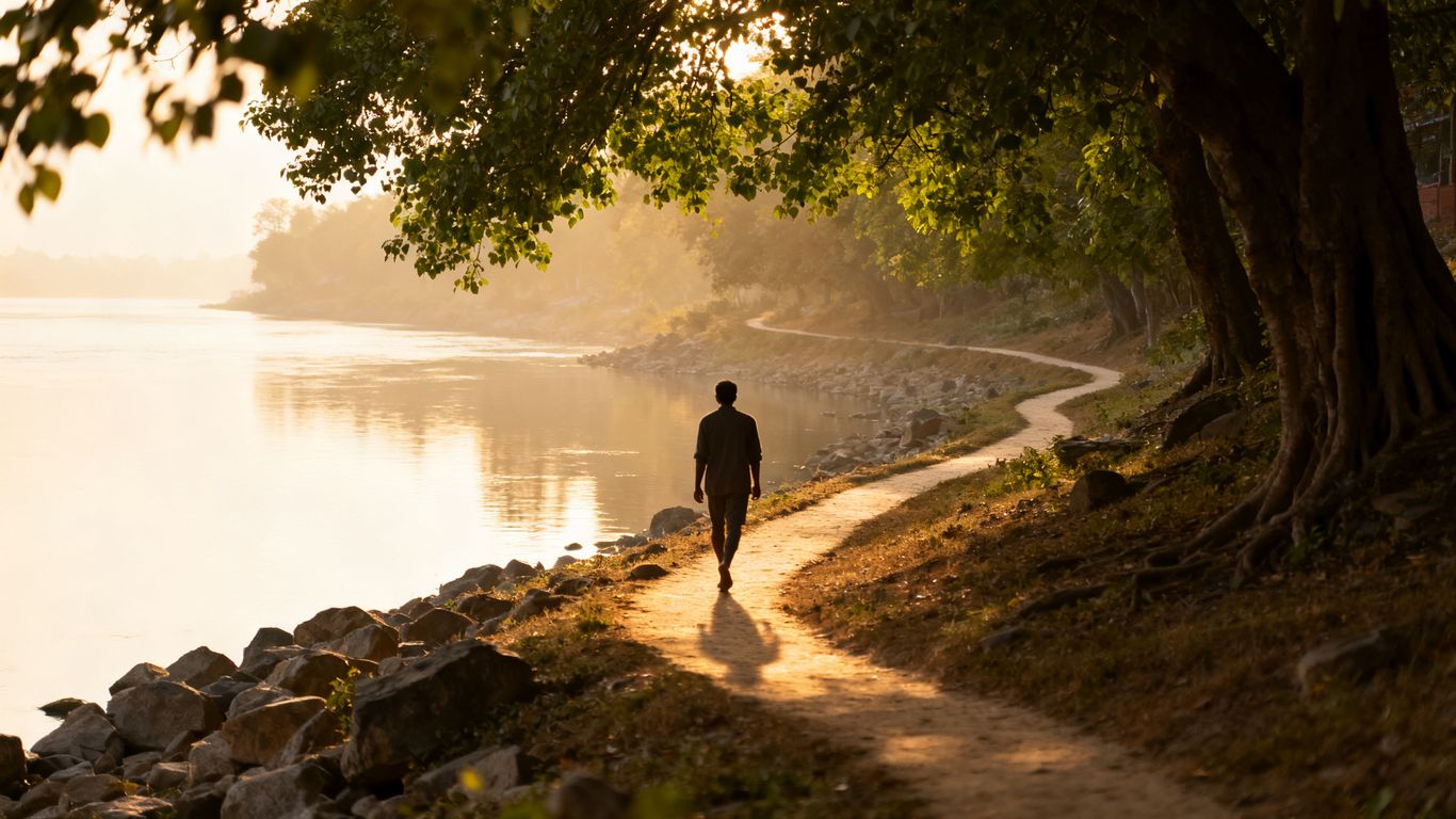 Peaceful riverbank path with sunlight and calm water.