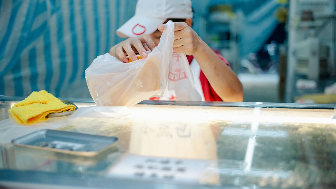 Vendor packing goods in a plastic bag.