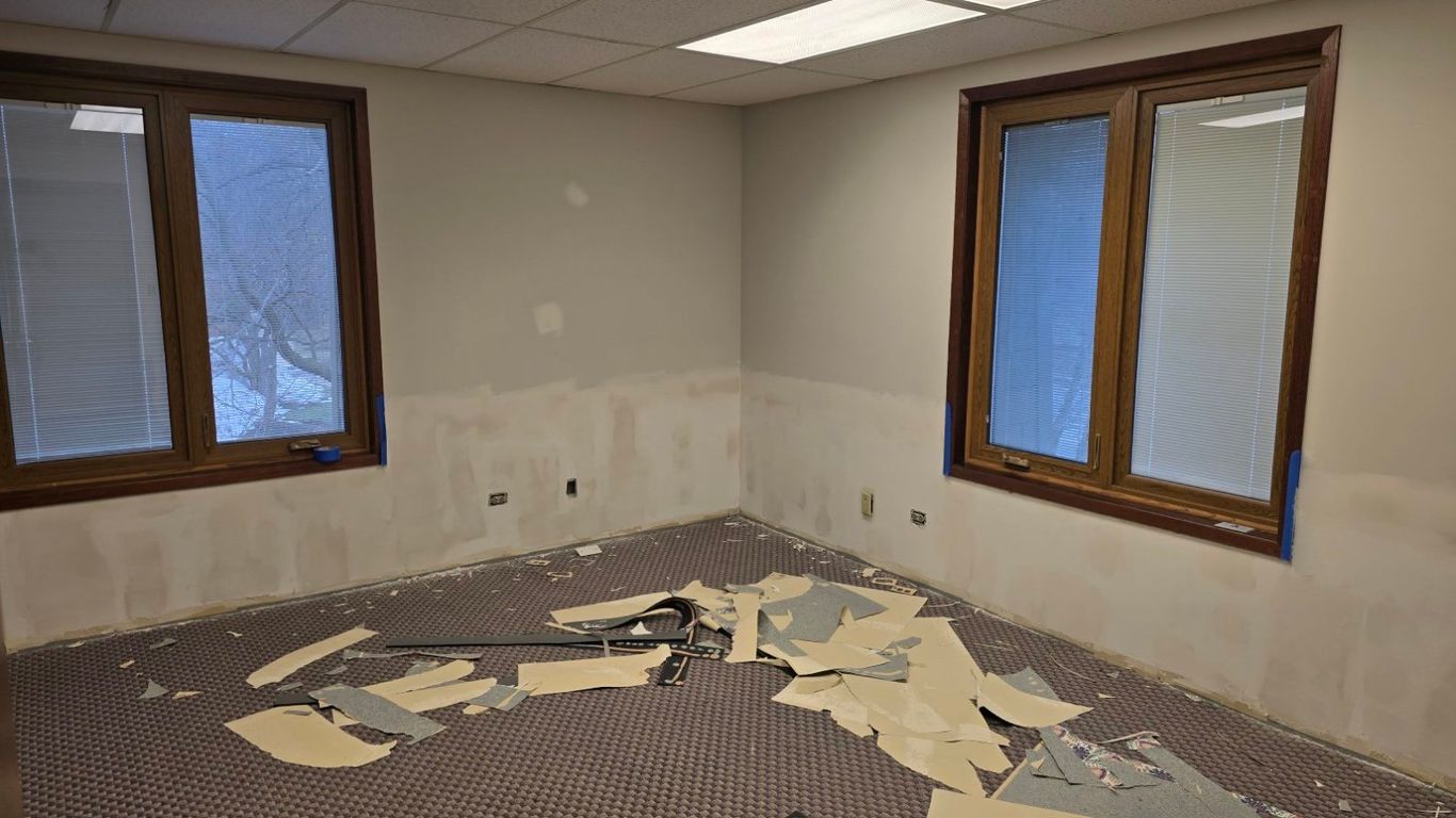 Room undergoing renovation with torn wallpaper and tools on the carpet.