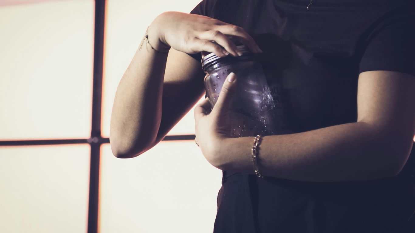 A woman standing in front of a window holding a bottle