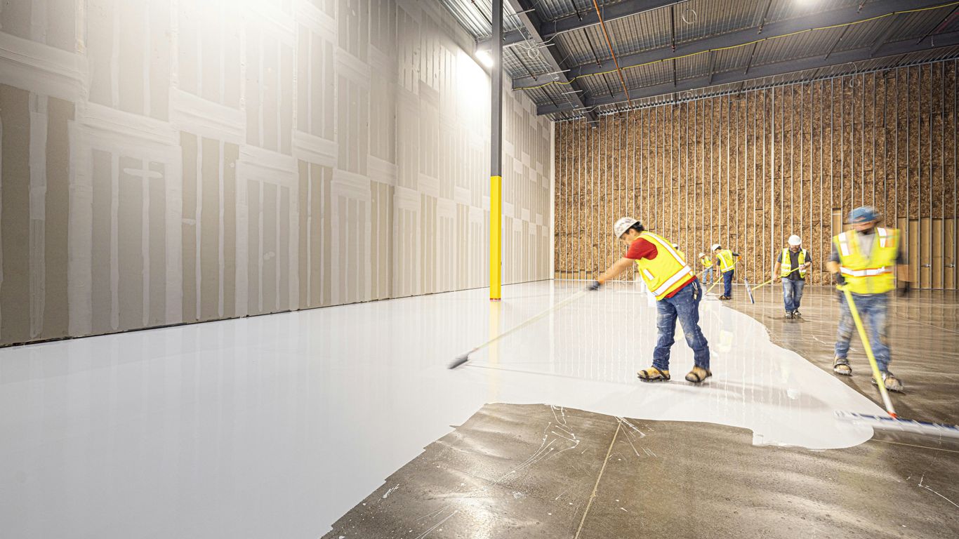 Workers painting a large industrial floor white