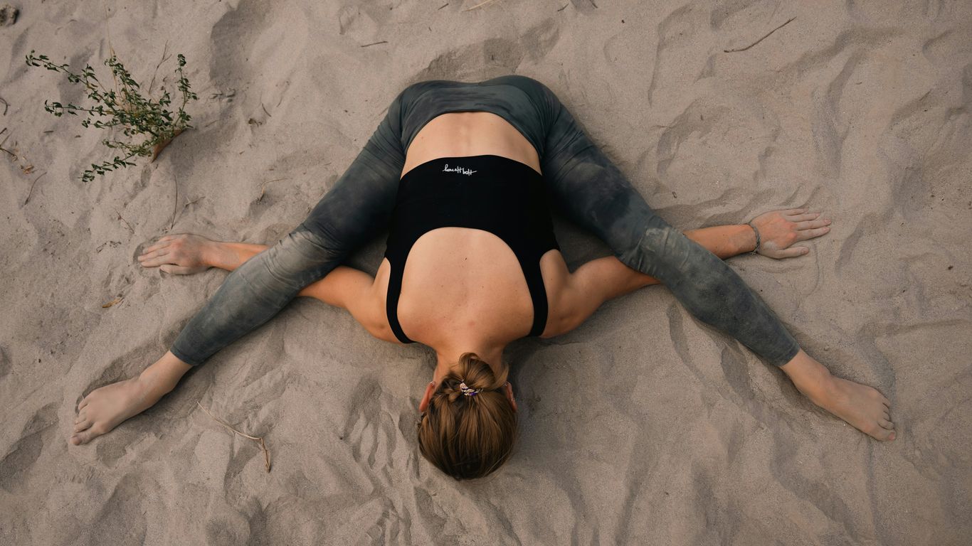 a woman laying on the sand with her back to the camera