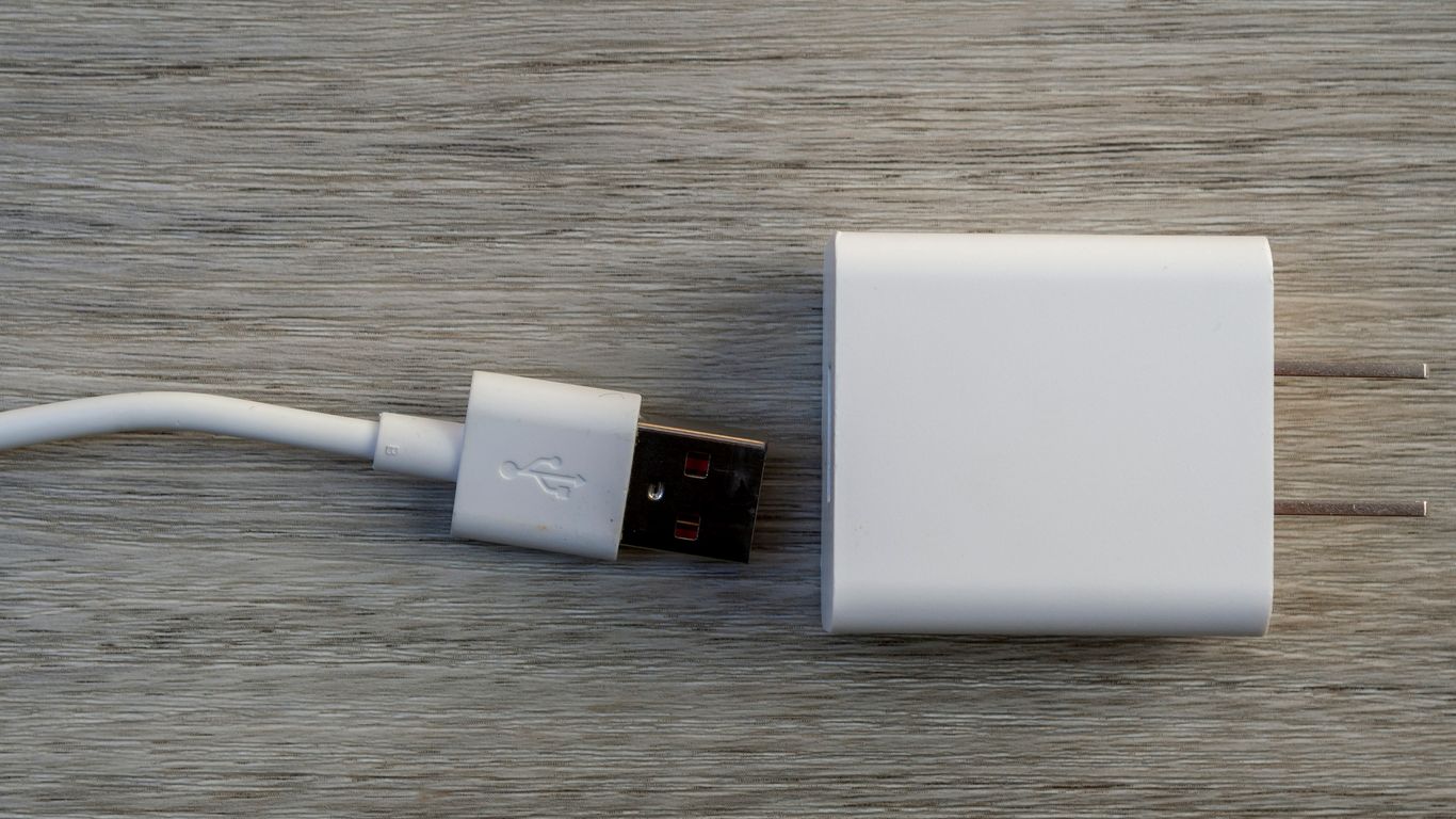 White usb charger and cable on wooden surface