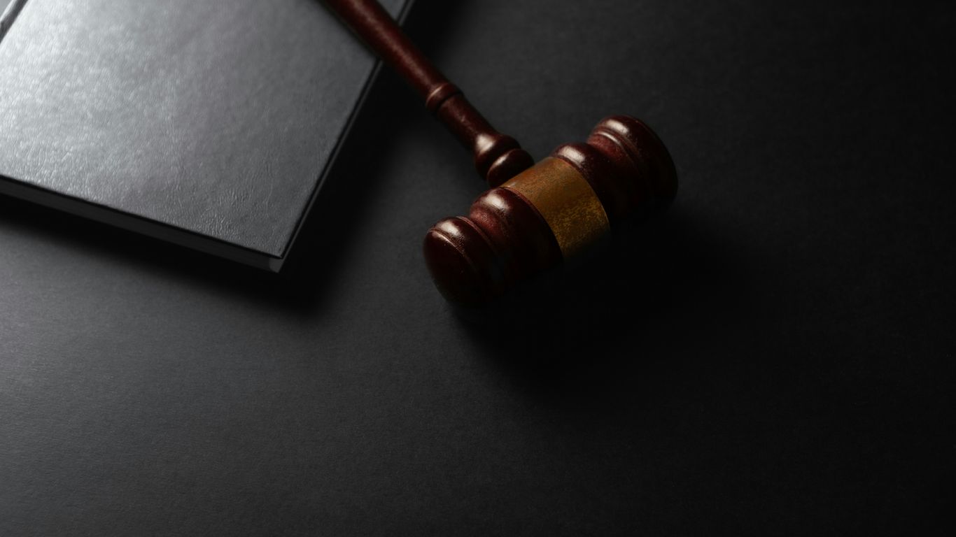 Wooden gavel resting on a dark surface next to book