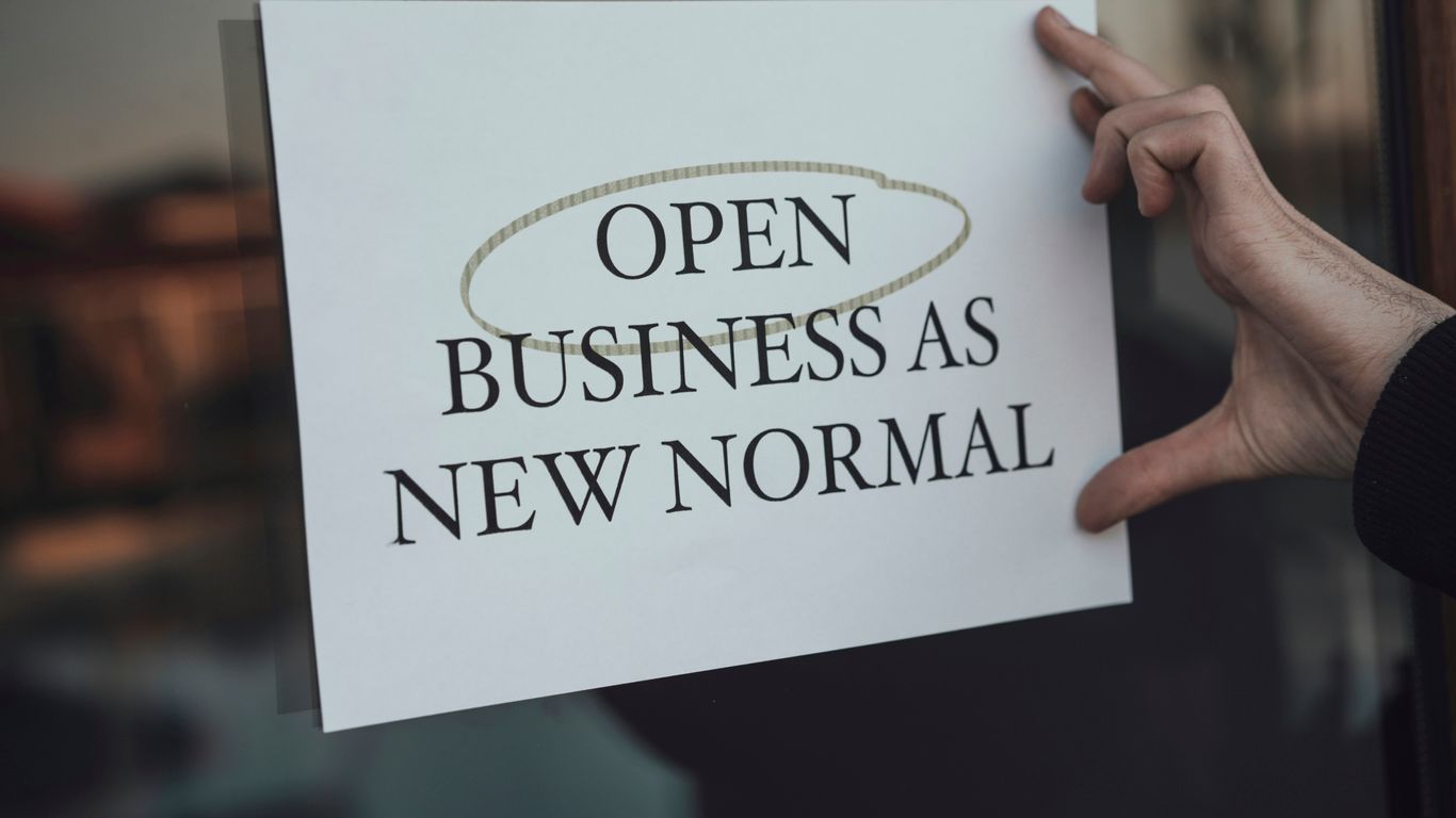 a person holding a sign that says open business as new normal